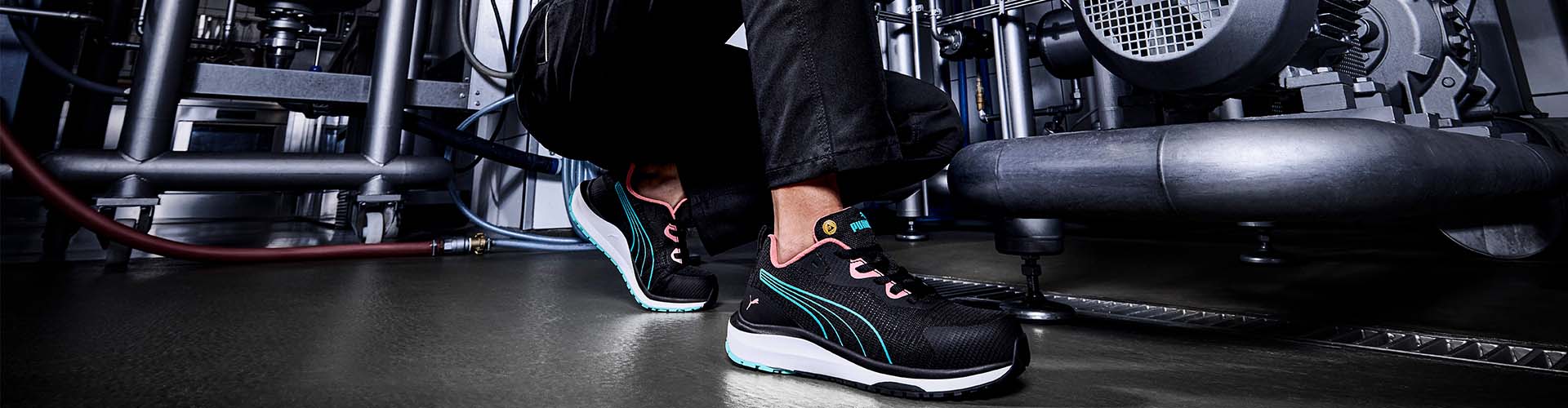 Leichter Sicherheitsschuh CELERITY KNIT BLUE/CORAL LOW S1PS ESD FO HRO SR in Schwarz mit blauen und korallfarbenen Details, getragen im industriellen Arbeitsumfeld.