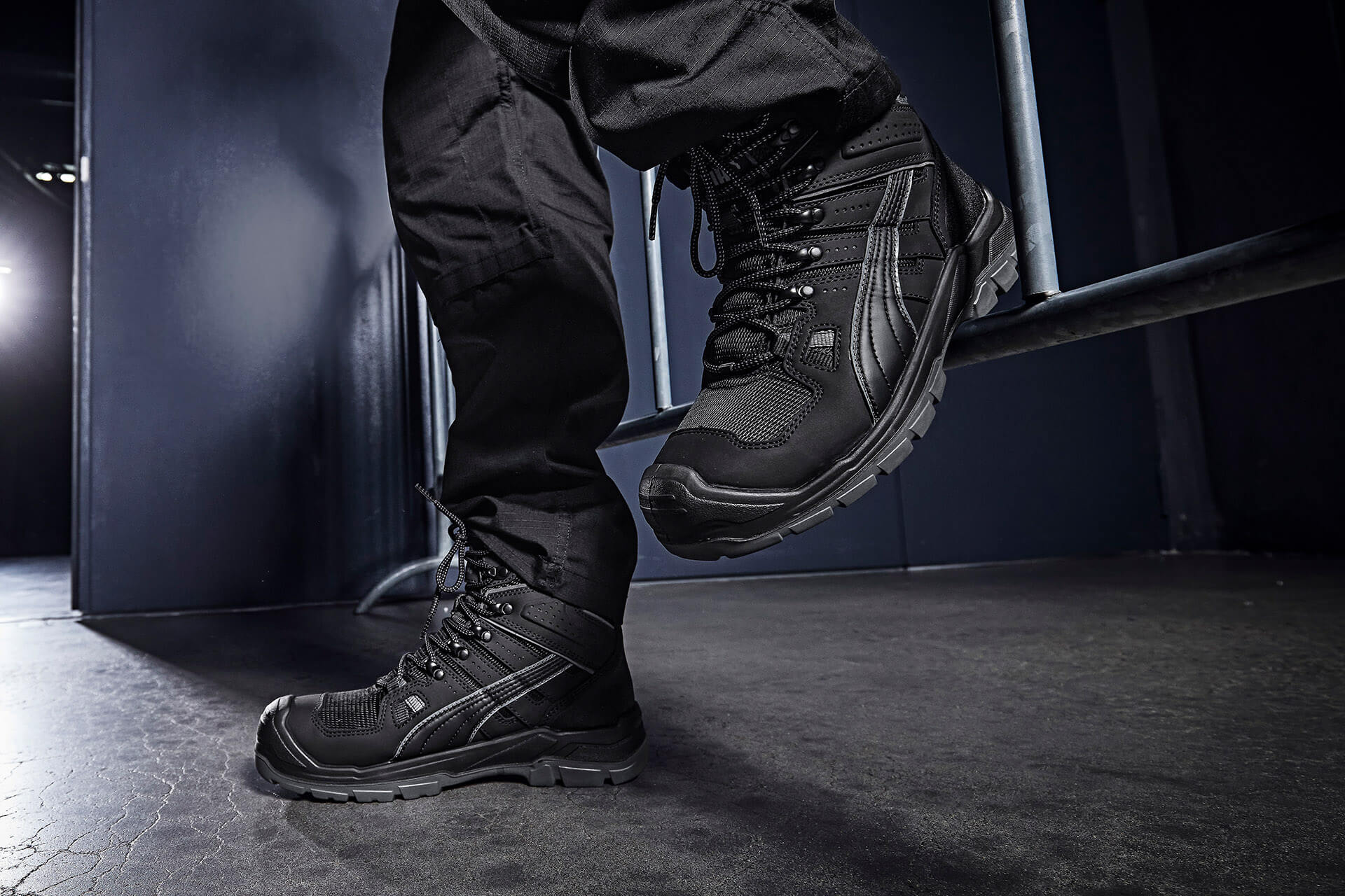 Schwarze PUMA SAFETY YOSEMITE ST CTX MID Schnürboots O2 mit Schnürung und profilierter Sohle, seitlich am Fuß getragen auf dunklem Boden.