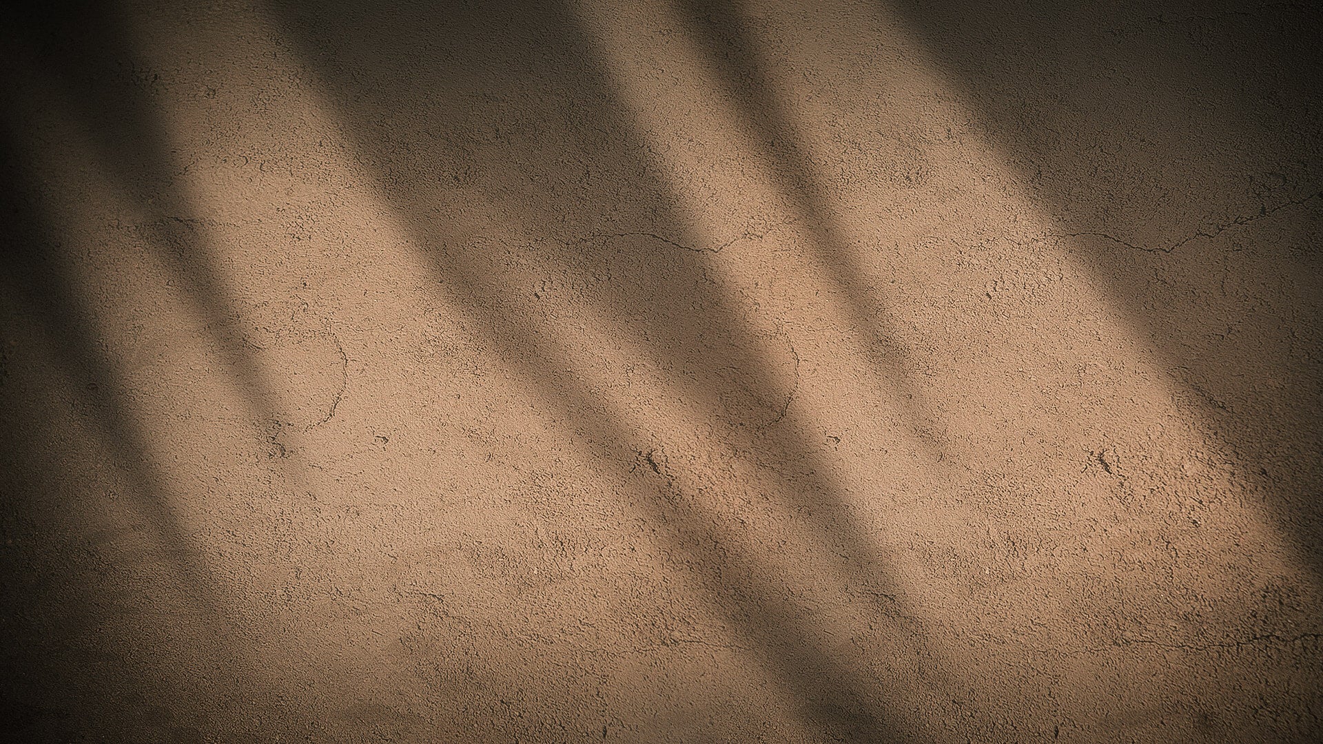 Braune Wandoberfläche mit rauer Struktur und Schattenverlauf.